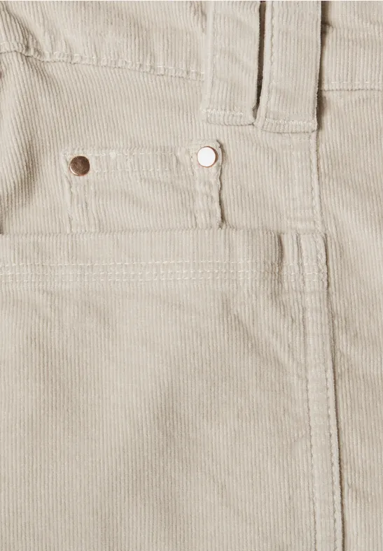 Gros plan d’un pantalon en velours côtelé beige avec poche avant et rivet métal