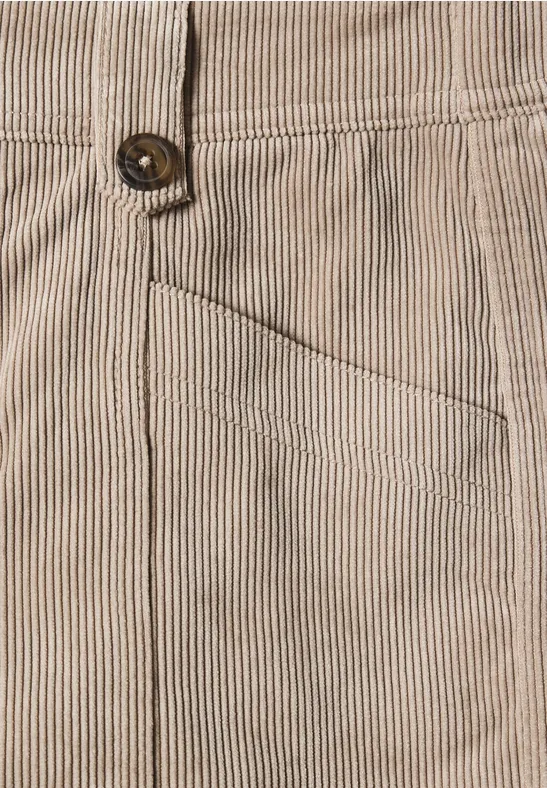 Gros plan d’un pantalon en velours côtelé beige à fines rayures, poche avant et bouton visibles