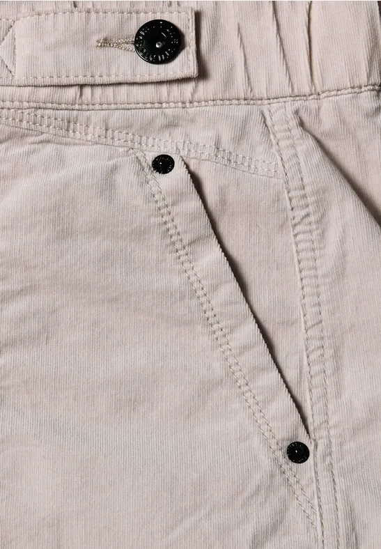 Nahaufnahme einer hellbeigen Hose aus Baumwolle mit sichtbarer Naht und schwarzen Knöpfen.