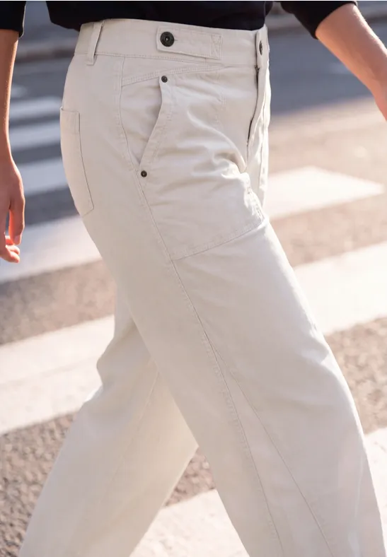 Eine Person trägt helle, weite Hose beim Überqueren einer Straße mit Zebrastreifen.