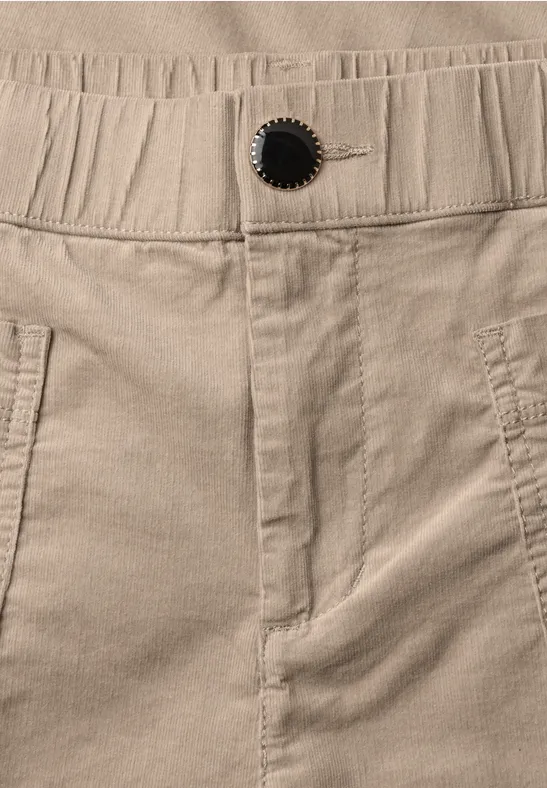 Beige Cordhose mit elastischem Bund, sichtbarem Knopf und seitlichen Eingrifftaschen.