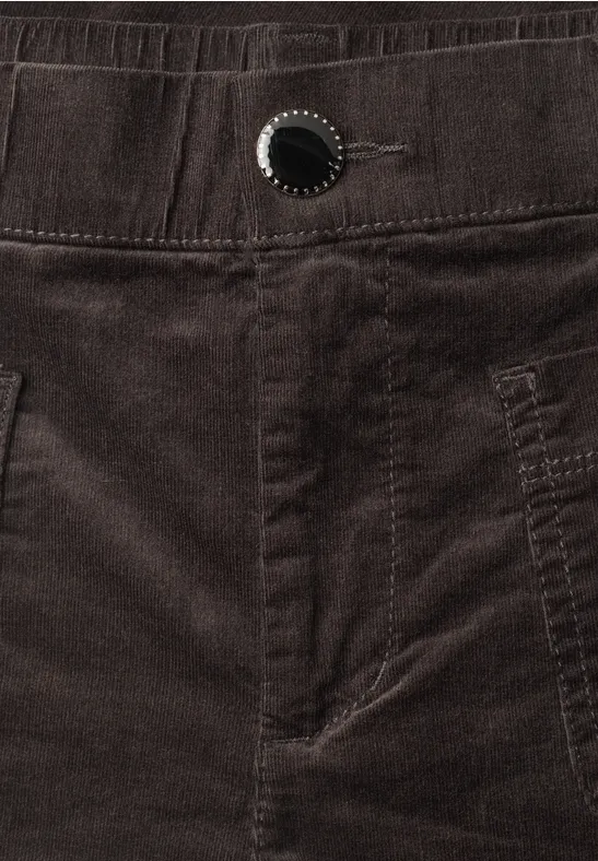Nahaufnahme einer dunkelbraunen Cordhose mit Bund, Gürtelschlaufen und Knopfdetail.