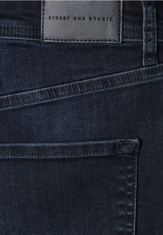 Nahaufnahme dunkler Jeans mit hinterer Tasche und Lederpatch 'Street One Studio' am Bund.