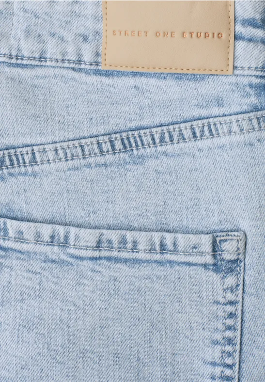 Nahaufnahme einer hellblauen Jeans mit Taschen, sichtbaren Nähten und Lederetikett.
