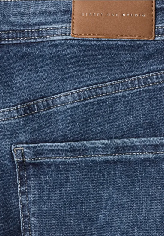 Close-up van blauwe spijkerbroek met stiksels en zak.