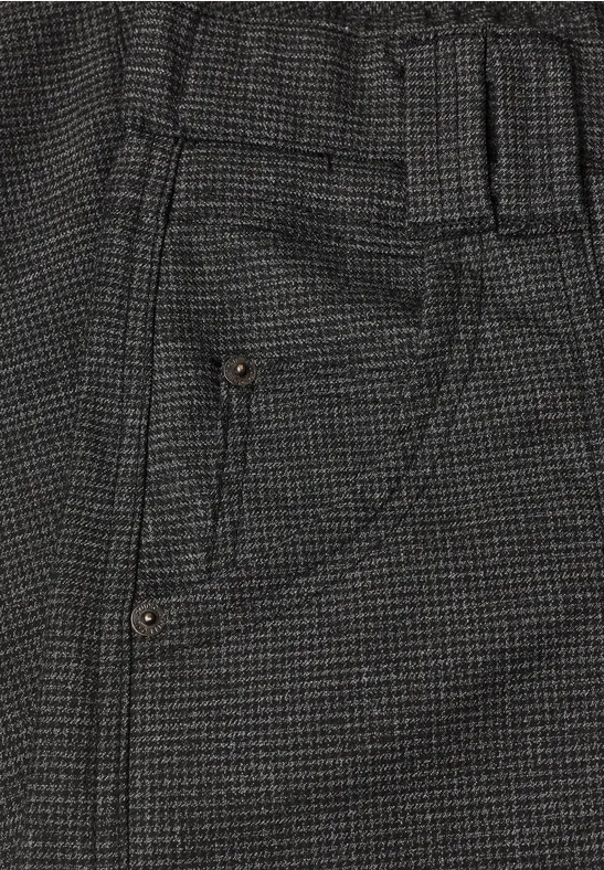 Detail einer grauen, karierten Hose mit Gummibund und seitlicher Tasche mit Ziernaht.