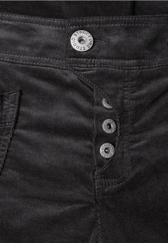 Plan rapproché d’un pantalon noir en tissu épais, orné de quatre boutons argentés à la taille.