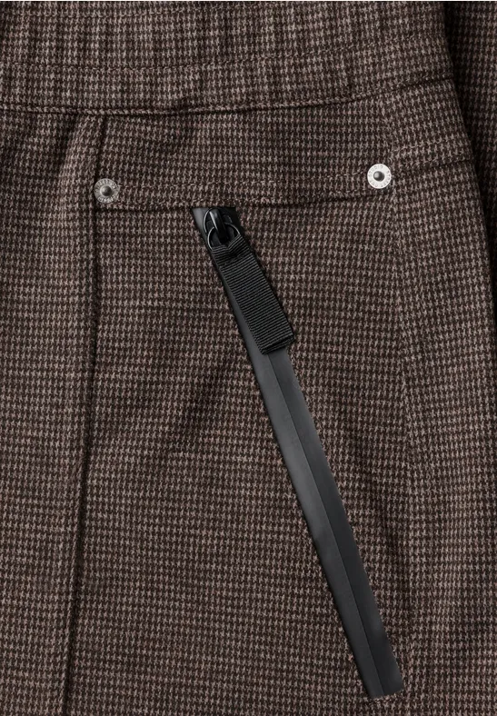 Braune karierte Stoffhose mit diagonaler, schwarzer Reißverschlusstasche und silbernen Nieten