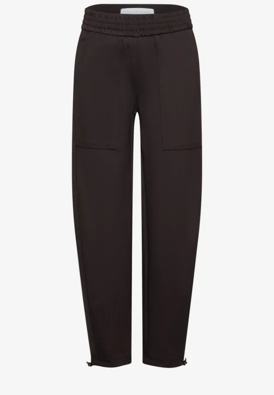 Schwarze Jogginghose mit elastischem Bund, aufgesetzten Taschen und Reißverschlüssen an den Knöcheln.