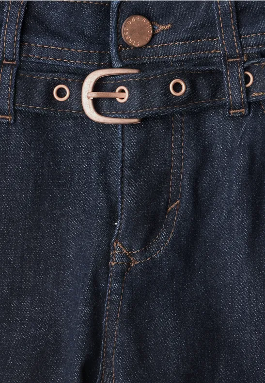 Gros plan sur un jean bleu foncé avec ceinture et œillets métalliques.