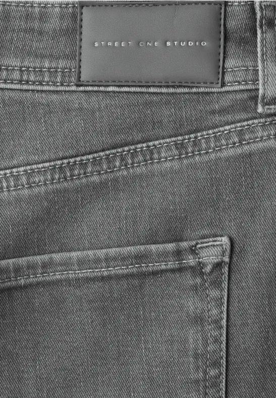 Nahaufnahme einer grauen Jeans mit Gesäßtasche und schwarzem Markenlabel 'Street One Studio'.