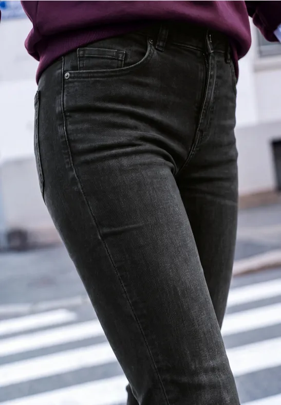 Close-up van een persoon met zwarte skinny jeans op een zebrapad.