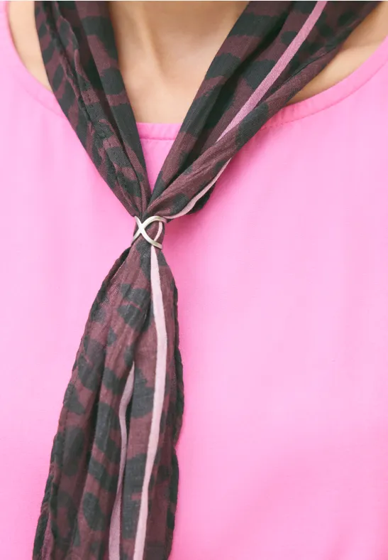 Gemusterter schwarzer-rosa Schal in Ringknoten über pinkem Shirt.