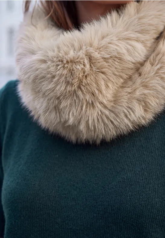 Gros plan: personne en pull vert avec col en fausse fourrure beige.