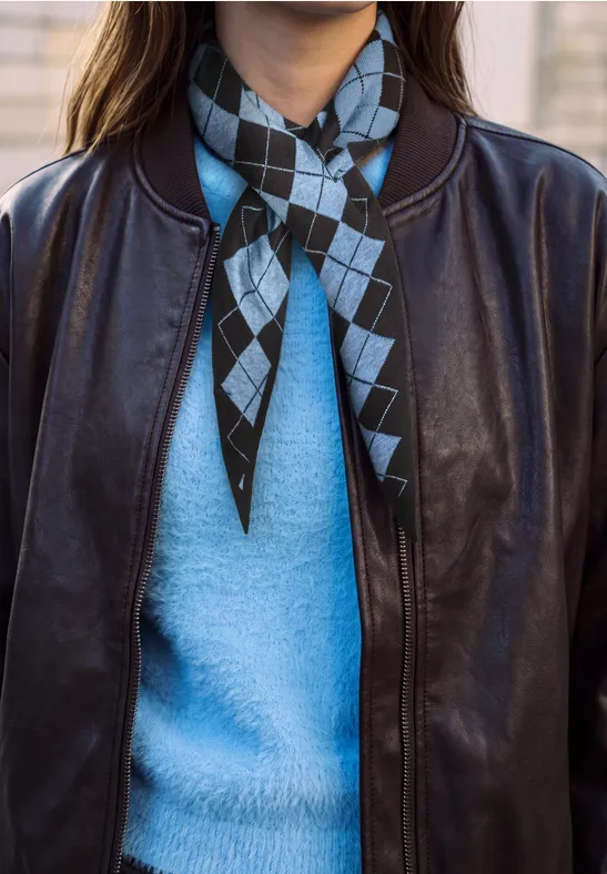 Schwarze Lederjacke über hellblauem Pullover, diamond-muster Halstuch in Schwarz und Hellblau.