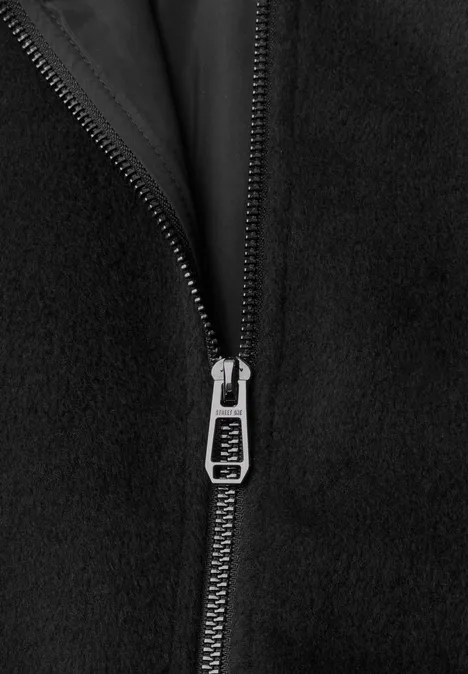 Close-up van een zilverkleurige ritssluiting op zwart fleece-stof.