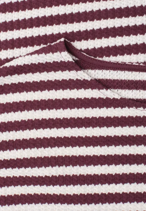 Close-up van een rood-wit gestreept gebreid kledingstuk met een opgestikte zak.