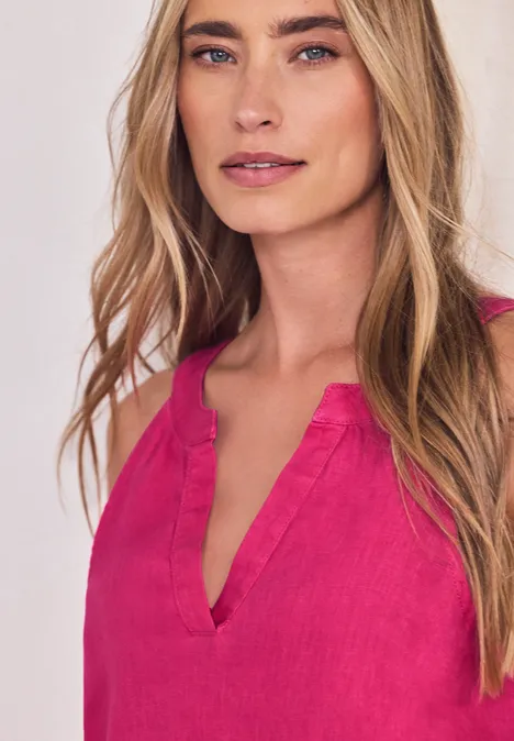 Een vrouw draagt een mouwloze fuchsia roze top met V-hals.