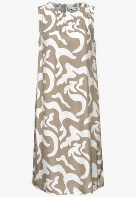 Mouwloze midilengte A-lijnjurk in beige met een wit, abstract patroon.