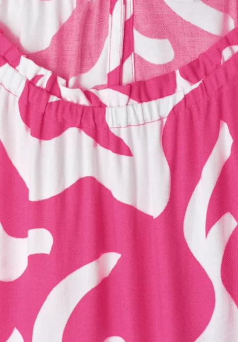 Nahaufnahme eines rosa-weißen Kleidungsstücks mit abstraktem Muster und elastischem Ausschnitt.