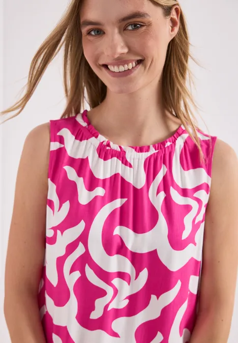 Kind trägt ärmelloses Oberteil mit pink-weißem abstraktem Muster.