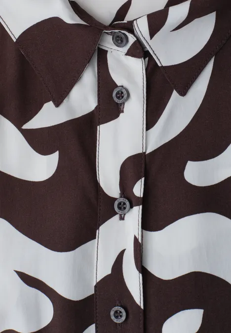 Nahaufnahme eines Hemds mit organischem schwarz-weißem Muster und schwarzen Knöpfen.