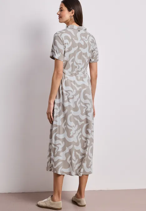 Frau von hinten in Midi-Kleid mit beigem abstraktem Muster, kurzen Ärmeln und hohem Ausschnitt