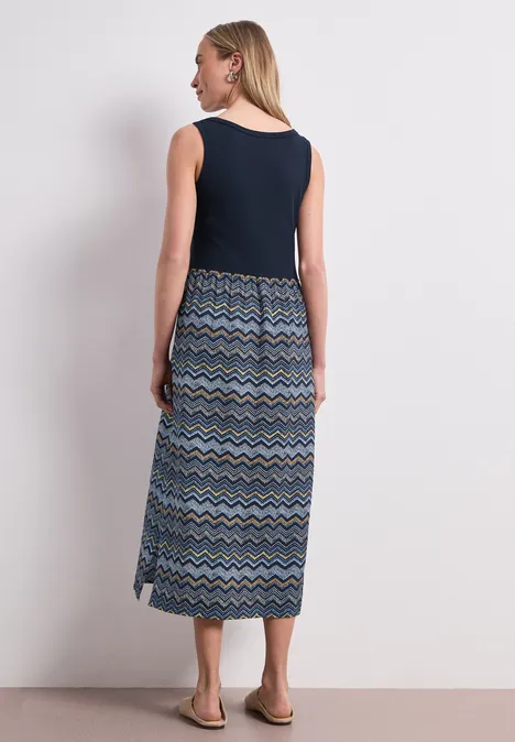 Midi-Kleid mit Strukturrock deep blue Frau von hinten seitlich, trägt ärmelloses dunkelblaues Top und gemusterten Maxirock mit Sandalen.