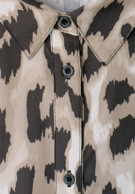 Close-up van een beige-bruin overhemd met dierenprintvlekken en zwarte knopen.
