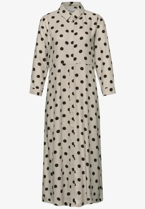 Robe midi beige à col chemise, manches longues et pois noirs.