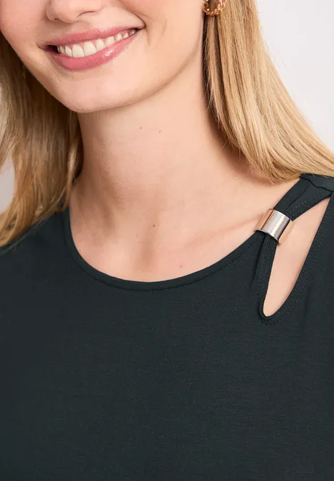 Frau mit blondem Haar und Lächeln, trägt schwarzes Top mit Cut-out-Schulter und Metallring