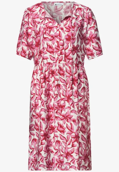 Robe mi-longue à manches courtes, motif floral rose et blanc, col en V et ceinture à la taille.