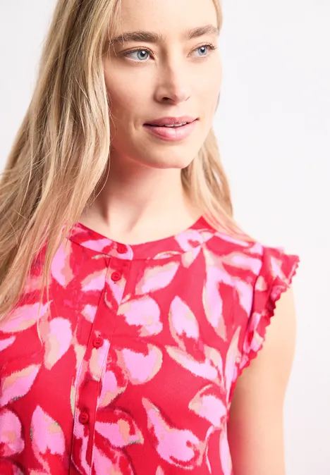 Femme portant un top sans manches à motif floral rose-rouge vif.