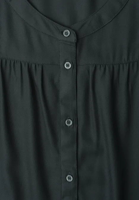 Blouse noire à encolure ronde et patte de boutonnage centrale.