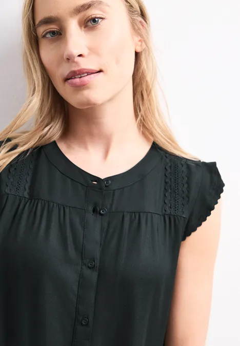 Femme portant un top noir sans manches avec dentelle aux épaules.