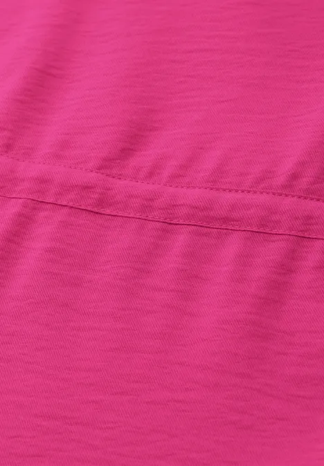 Zbliżenie na różowy materiał z widocznym poziomym szwem.