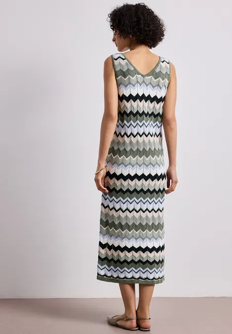 Femme de dos en robe midi sans manches à motif zigzag coloré, avec des sandales.