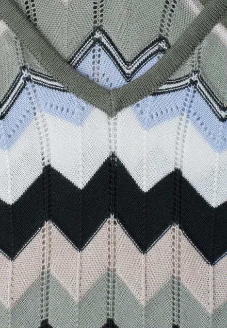 Gros plan d’un pull tricoté à motif chevrons multicolores en gris, bleu clair, blanc, noir et beige.
