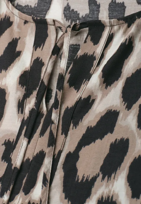 Nahaufnahme eines Bekleidungsstücks mit Leopardenmuster in Beigetönen und schwarzen Flecken.