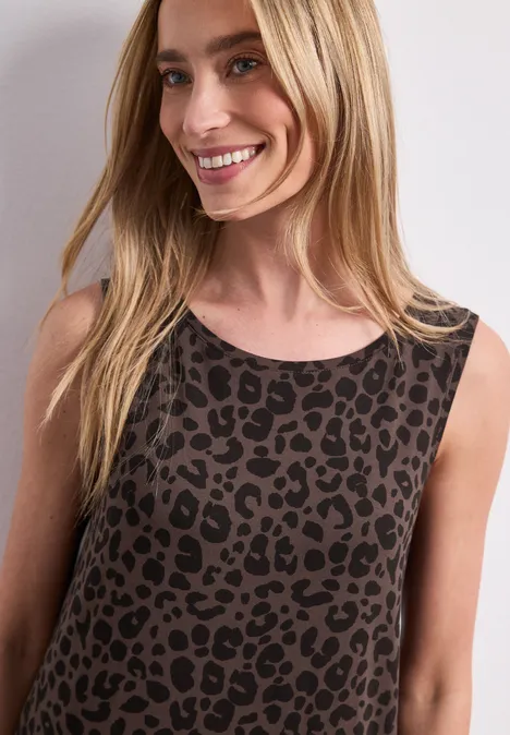 Jersey midi-jurk met leoprint molten earth Een glimlachende blonde vrouw draagt een mouwloze top met luipaardprint.