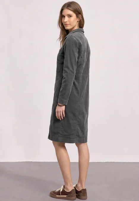 Kniehoge jurk van corduroy met ritssluiting gravel grey Vrouw in zijaanzicht draagt een grijze corduroy midi-jurk voor een neutrale achtergrond.