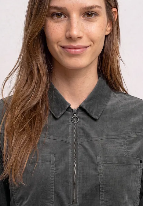 Kniehoge jurk van corduroy met ritssluiting gravel grey Een vrouw draagt een grijs denimoverhemd met ritssluiting en kraag, kijkt recht in de camera.