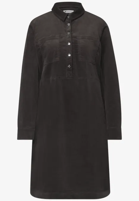 Schwarzes Cordkleid im Hemdstyle mit Kragen, halber Knopfleiste, Brusttaschen und langen Ärmeln.