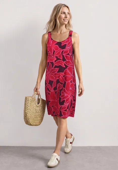 Knielanges Kleid mit gerafften Trägern salsa red Frau in knielangem, ärmellosem rotem Kleid mit großem Blumenmuster, trägt Korbtasche und weiße Sneakers