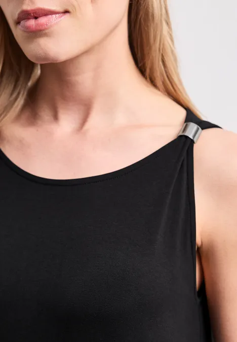 Knielanges Kleid mit Schnallendetail Black Detailaufnahme: Frau im schwarzen ärmellosen Oberteil mit silberner Schulterapplikation, Fokus auf Hals und Schulter.