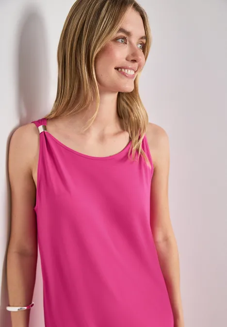 Knielanges Kleid mit Schnallendetail magenta dream Frau trägt rosa ärmelloses Top mit Ringdetails, steht vor hellem Hintergrund.