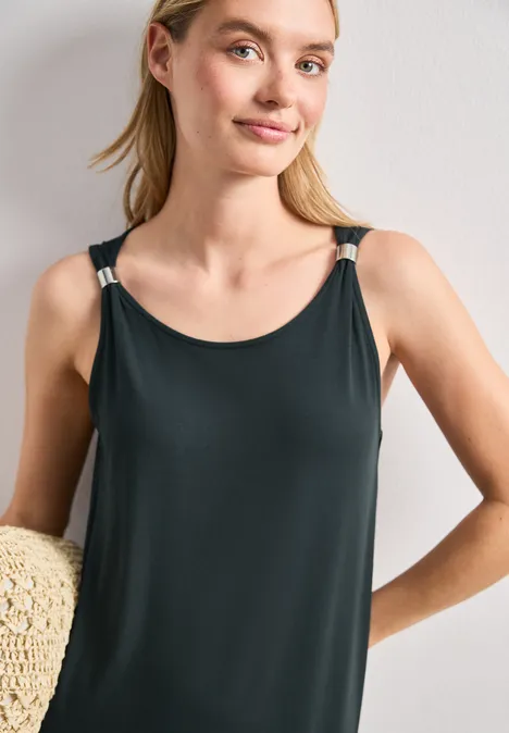 Robe longueur genou avec détail de boucle deep bound green Une femme porte un débardeur noir à fines bretelles et tient un chapeau de paille.