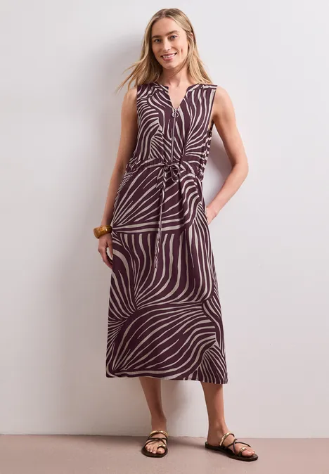 Midi-Kleid mit Split Neck und Zipper rustic rouge Frau trägt ärmelloses Midikleid mit Zebramuster, Wickeloptik und flachen Sandalen.