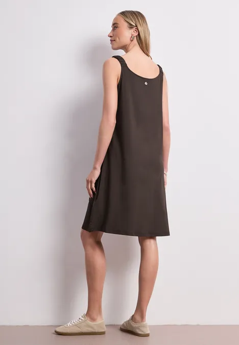 Knielanges Kleid mit gerafften Trägern espresso brown Eine Frau in einem ärmellosen, braunen Kleid und hellen Sneakern steht seitlich vor neutralem Hintergrund.