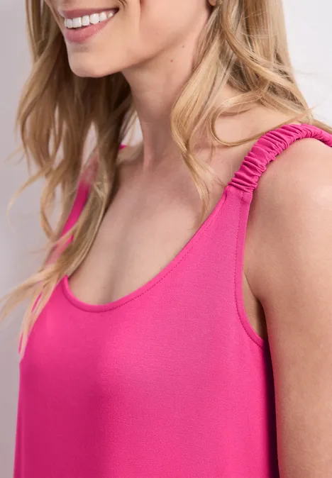 Knielanges Kleid mit gerafften Trägern magenta dream Seitliche Nahaufnahme einer lächelnden Frau in einem knallig-pinken ärmellosen Oberteil.